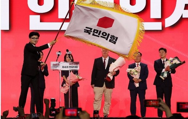 국민의힘 한동훈 당대표 당선자가 23일 오후 경기도 고양시 킨텍스에서 열린 국민의힘 제4차 전당대회에서 황우여 비상대책위원장으로부터 당기를 전달받아 흔들고 있다. 사진=공동취재