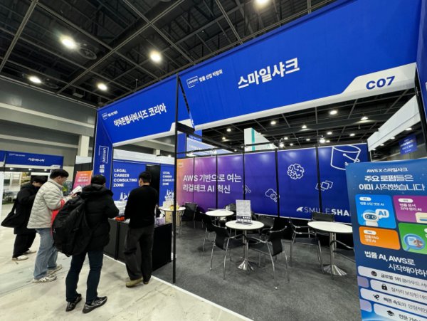  대한민국 법률산업 박람회 2025 스마일샤크 × AWS 공동 부스에서 스마일샤크 직원이 방문객에게 AI 도입 서비스를 소개하고 있다(사진=스마일샤크)